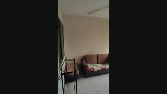 Room features: beige painted walls, floor tiles, sofa in brown fabric, throw blanket on sofa, ceiling fan, window with metal frame, small table, decorative items on table.