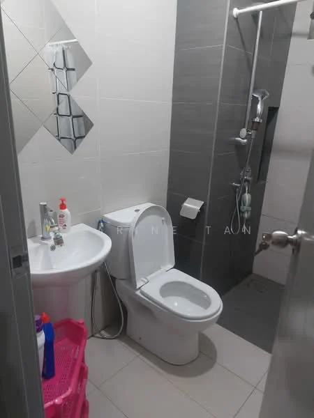 Bathroom features: white ceramic toilet, single-sink vanity with chrome faucet, mirror with geometric pattern, shower area with glass partition, handheld shower, wall-mounted showerhead, grey wall tiles, light-colored floor tiles, pink storage basket, toiletries on sink; style: modern.