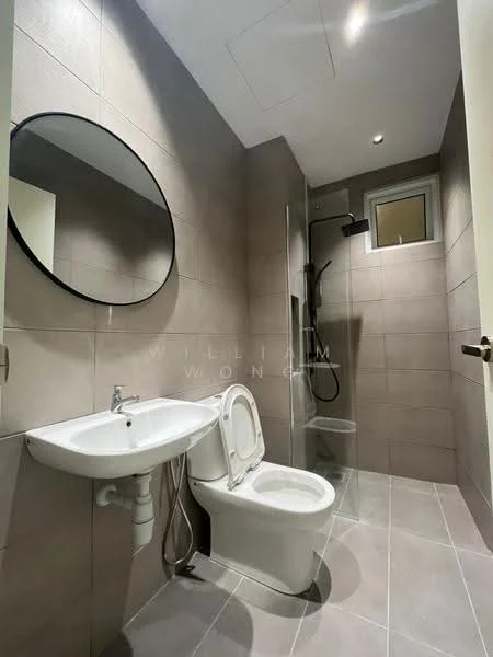 Bathroom features: grey tiled walls, light grey tiled flooring, round black-framed mirror, single-sink vanity with white basin, chrome basin mixer faucet, one-piece toilet, walk-in shower with glass enclosure, black shower head, shower wall with tile cladding, window for natural light; style: modern.