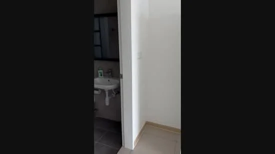 Room features: white painted walls, grey tiled flooring, single-sink vanity, mirror above sink, wall-mounted faucet, toilet, window with black frame.