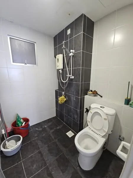 Bathroom features: white tiled walls, dark grey tiled flooring, shower area with wall-mounted shower head, toilet, small window, toilet paper holder, soap dish, cleaning supplies in corner.