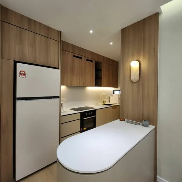 Kitchen features: white countertop, wood cabinetry, stainless-steel fridge, built-in oven, 4-burner gas hob, kitchen island, recessed LED downlights, white backsplash, microwave, sink, wall-mounted cabinet, drawer storage; style: modern.
