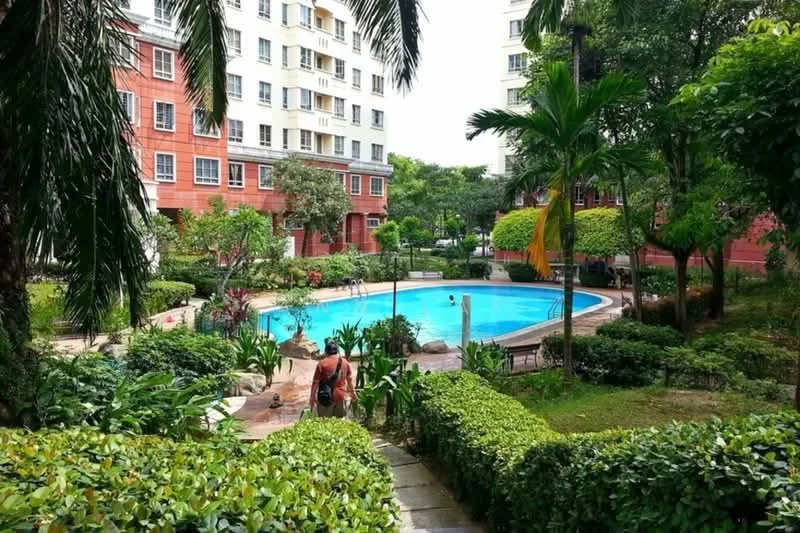 Exterior type: low-rise apartment block; features: swimming pool, landscaped garden, manicured lawn, palm trees, tropical landscaping, stone-paved walkway, surrounded by greenery, multiple residential buildings, outdoor seating area; style: modern.