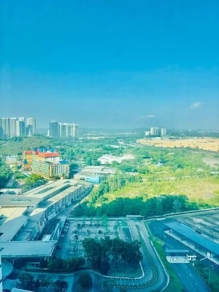 Exterior type: high-rise condominium; features: city skyline view, surrounded by greenery, multi-storey buildings in the background, open landscape, parking area visible, roadway with interlocking pavers; style: modern.