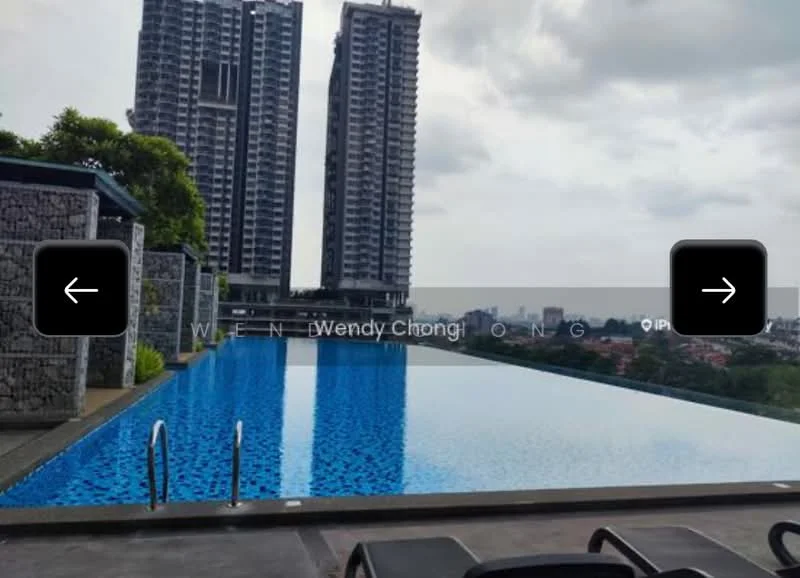 Exterior type: high-rise condominium; features: infinity pool, pool deck with loungers, surrounded by greenery, city skyline in background, two tall residential towers, stone-clad walls, blue tiled pool surface; style: modern.