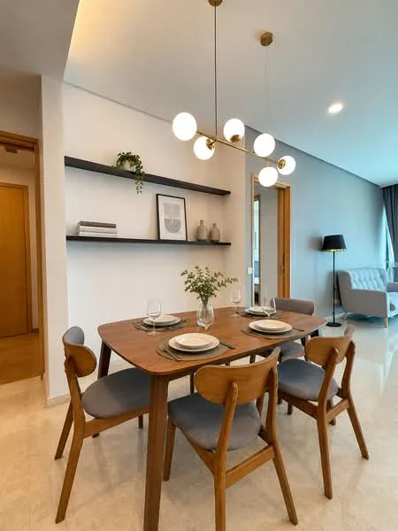 Dining features: wooden dining table, 4 dining chairs with grey upholstery, decorative vase with flowers on table, wall-mounted shelves, framed artwork on wall, pendant light fixture with multiple bulbs, cream walls, marble tile flooring, large window with sheer curtains, grey accent wall, side table with lamp; style: modern.