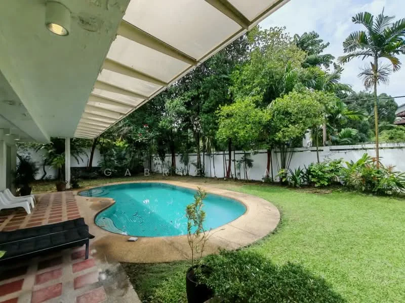 Exterior type: detached bungalow; features: swimming pool, landscaped garden, manicured lawn, tropical landscaping, patio area with roof, outdoor seating area, surrounded by greenery, paved walkway; style: tropical-modern.