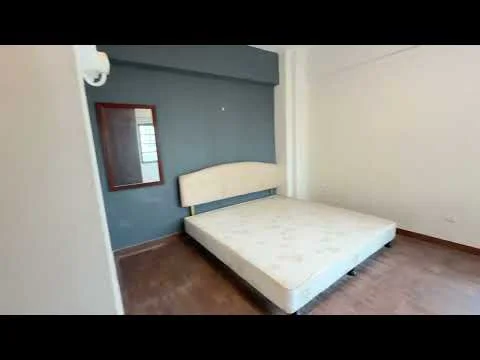 Bedroom features: wooden flooring, grey accent wall, white painted walls, unframed mirror, queen-size bed frame without mattress, air conditioning unit, window with natural light, baseboard trim; style: modern.
