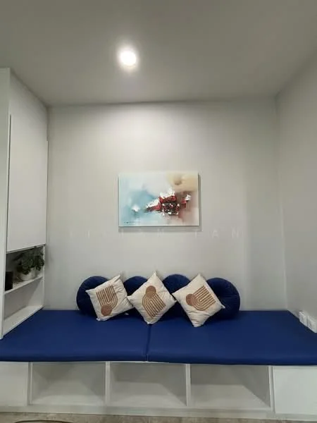 Room features: blue upholstered bench seating, decorative throw pillows, framed artwork on wall, white painted walls, recessed ceiling light, built-in shelving unit; style: modern.