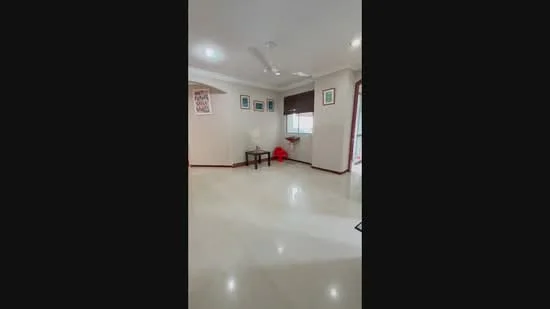 Living features: white painted walls, marble flooring, recessed downlights, 5-blade ceiling fan, large window with blinds, decorative artwork on walls, small side table, red decorative item; style: modern.