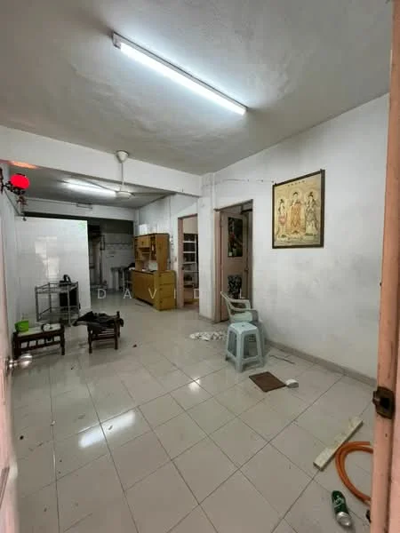 Room features: white painted walls, tile flooring, ceiling with fluorescent lights, wall-mounted ceiling fan, wooden door frames, framed artwork on wall, open layout, furniture including small chairs and a stool, kitchen area visible in background, shelves in background; style: minimalist.
