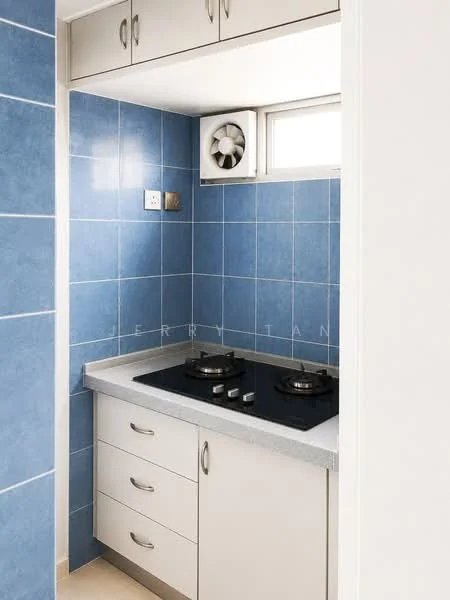 Kitchen features: blue tiled walls, light grey countertop, built-in gas stove with two burners, white cabinetry with handles, ventilation fan, window above countertop, drawer storage, wall-mounted electrical outlet; style: modern.