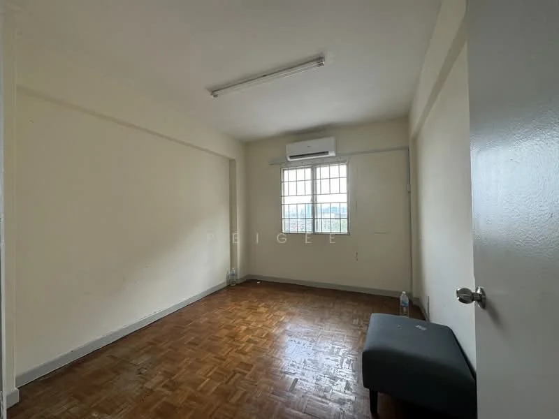 Room features: white painted walls, parquet wood flooring, 1 wall-mounted split AC, single window with grid pattern, ceiling light fixture, empty space, water bottle on floor, small bench or stool.