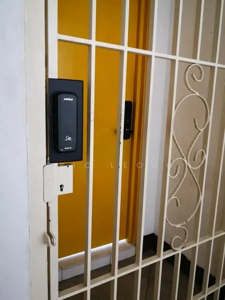 Room features: yellow painted door, metal security gate, keypad entry system, white wall, black floor tiles, door handle, lock mechanism; style: modern.