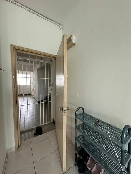 Room features: light grey painted walls, white tiled flooring, wooden door, metal shoe rack, security grille door, natural light from window, open space leading to another room.