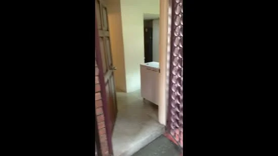 Room features: wooden door, metal security gate, concrete flooring, painted walls, visible hallway, light fixture, entrance area.