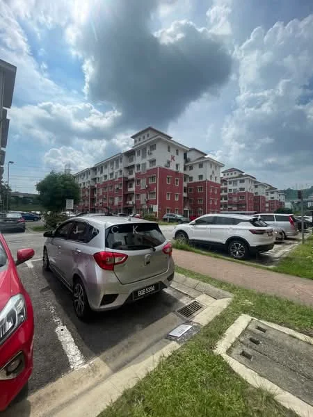 Exterior type: low-rise apartment block; features: red painted facade, white window frames, multiple storeys, balconies on upper floors, surrounded by greenery, parking spaces visible, cloudy sky, sidewalk, grass area; style: modern.
