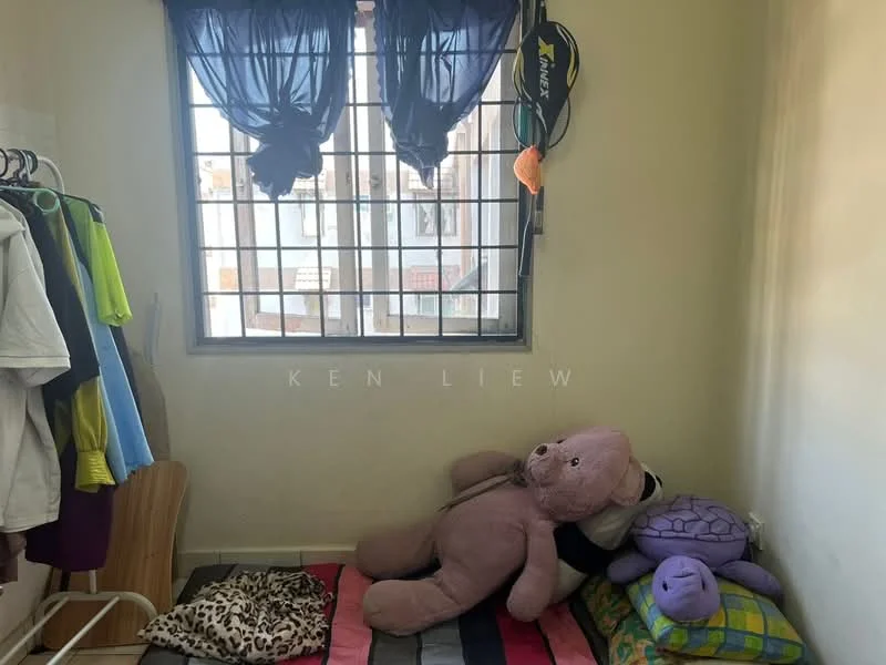 Room features: window with metal grille, blackout curtains, light-colored painted walls, wooden bed frame, colorful bedding, stuffed animals, clothing rack, flooring with carpet, tiled flooring.