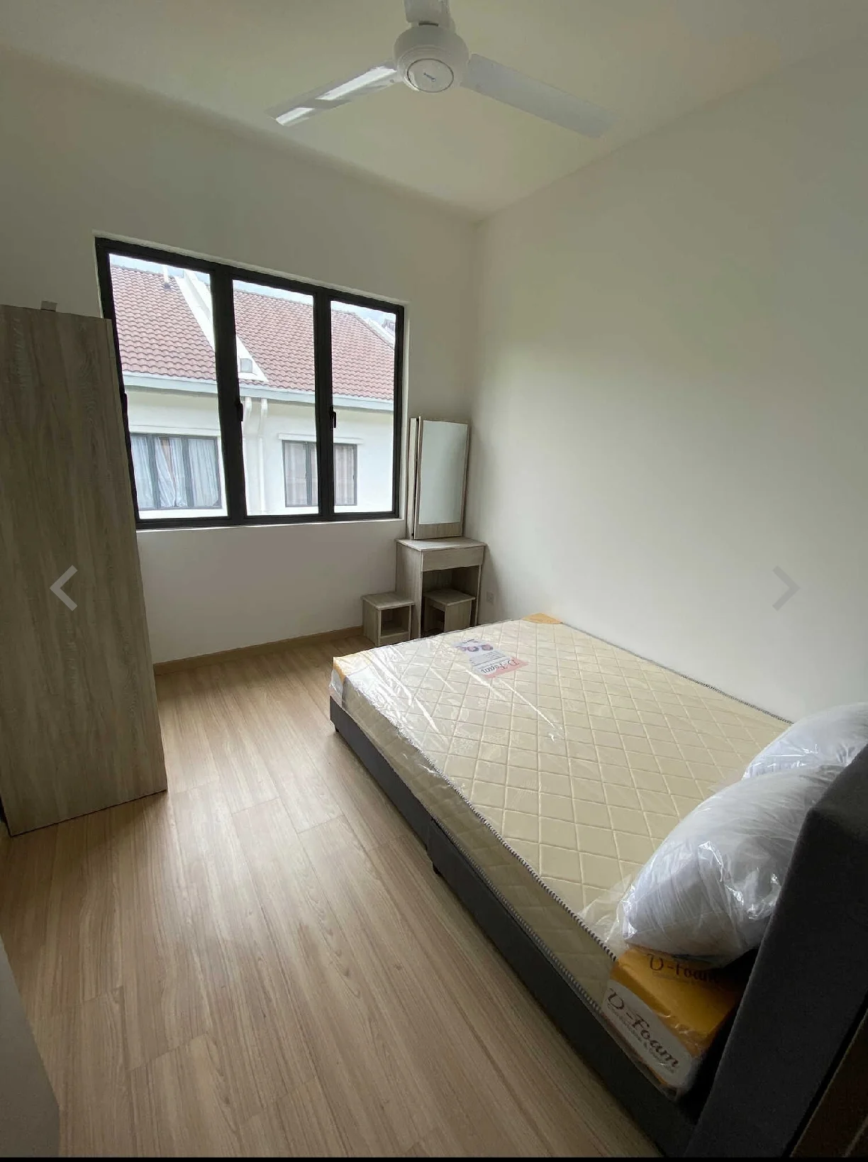 Bedroom features: queen-size bed, mattress with protective cover, wooden flooring, ceiling fan, large window with black frame, curtains, built-in wardrobe, mirror on dresser, nightstand with storage; style: modern.