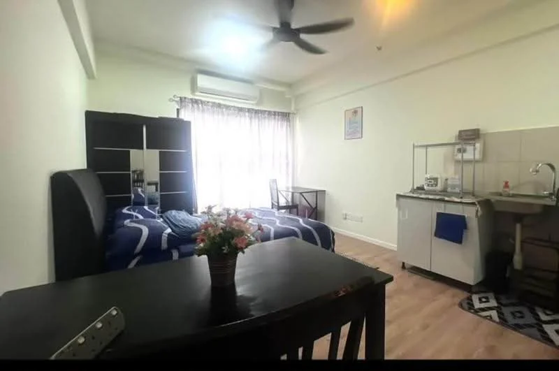 Bedroom features: 2 single beds with blue bedding, black upholstered headboard, wooden flooring, ceiling fan, window with sheer curtains, small dining table with 2 chairs, kitchenette with sink and countertop, refrigerator, decorative plant on table, wall-mounted air conditioning unit, framed artwork on wall; style: modern.