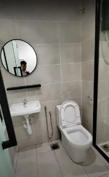 Bathroom features: white tiled walls, grey tiled flooring, round mirror, single-sink vanity, chrome basin mixer faucet, one-piece toilet, shower area with glass enclosure, wall-mounted showerhead; style: modern.