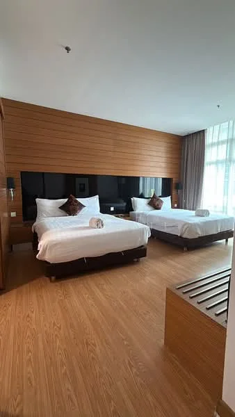 Bedroom features: two queen-size beds with white bedding, wooden accent wall, floor-to-ceiling windows with sheer curtains, laminate wood flooring, two bedside tables, decorative throw pillows, wall-mounted lamps, built-in wardrobe, bench seating at foot of bed; style: modern.