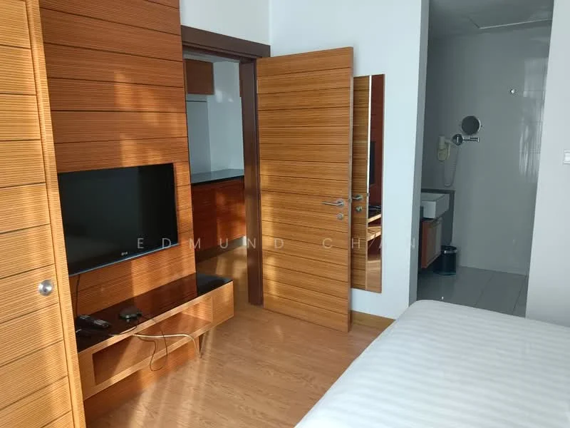 Bedroom features: wood paneling on walls, light wood flooring, built-in wardrobe with sliding doors, wall-mounted TV, TV console with storage, queen-size bed with white bedding, modern door with horizontal slats, natural light from window, neutral color scheme; style: modern. Bathroom features: shower area with glass enclosure, modern shower head, white sink with cabinet, toilet, tile flooring, neutral color scheme; style: modern.