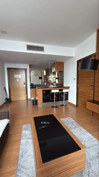 Living features: wooden flooring, white painted walls, recessed downlights, wall-mounted TV, coffee table with black top, sofa with cushions, decorative area rug, open kitchen layout, bar counter with stools, kitchen cabinetry, glass sliding door, pantry area; style: modern.
