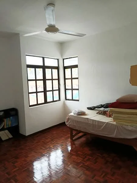 Bedroom features: wooden flooring, white painted walls, 5-blade ceiling fan, two large windows, single bed with mattress, stack of mattresses, bookshelf, decorative pillows.