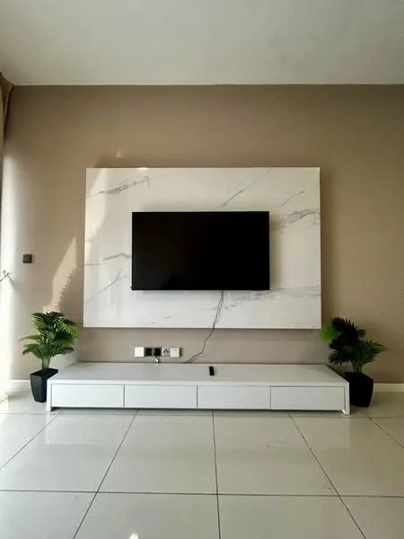 Living features: white marble feature wall with grey veining, wall-mounted flat-screen TV, white TV console with drawers, two potted plants, cream painted walls, glossy white tile flooring, natural light from window, minimalist decor; style: modern.