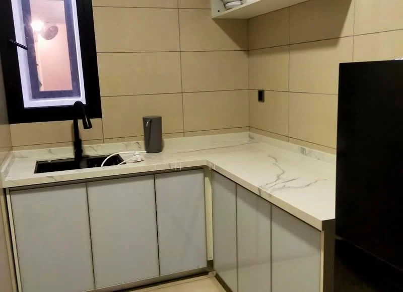 Kitchen features: white marble countertop, single-bowl stainless-steel sink, black gooseneck faucet, glass-front lower cabinets, white upper cabinets, tile backsplash, black refrigerator, recessed lighting, window with black frame; style: modern.