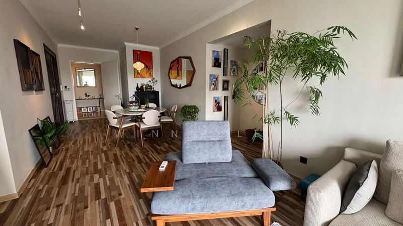 Living features: grey fabric sofa, wooden side table, area rug with geometric pattern, wall-mounted TV, decorative wall art, potted indoor plant, laminate wood flooring, recessed downlights, large window with natural light; style: modern. Dining features: round dining table, white upholstered dining chairs, decorative mirror, wall art, laminate wood flooring; style: modern.