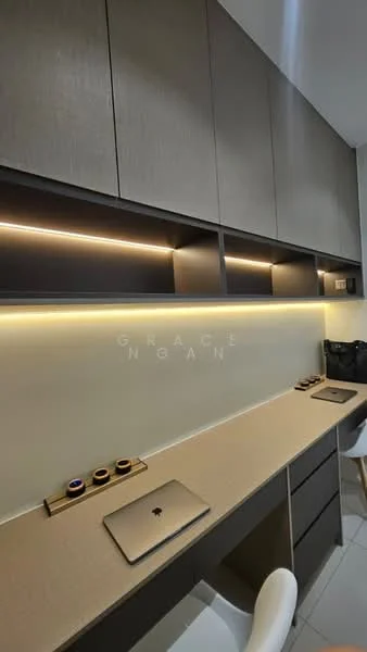 Study features: built-in cabinetry with grey finish, under-cabinet LED lighting, light beige countertop, white wall, minimalist design, single wall-mounted electrical outlet, wooden desk with laptop, decorative items on countertop, white chair; style: modern.