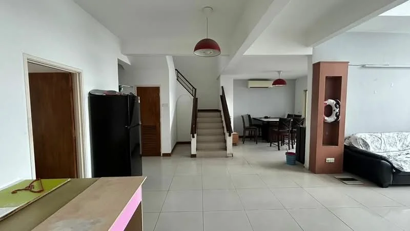 Living features: white painted walls, tile flooring, 5-blade ceiling fan with light, sofa in black fabric, dining table with chairs, staircase leading to upper floor, refrigerator in black, air conditioning unit, decorative wall feature, light fixture with red shade; style: modern.