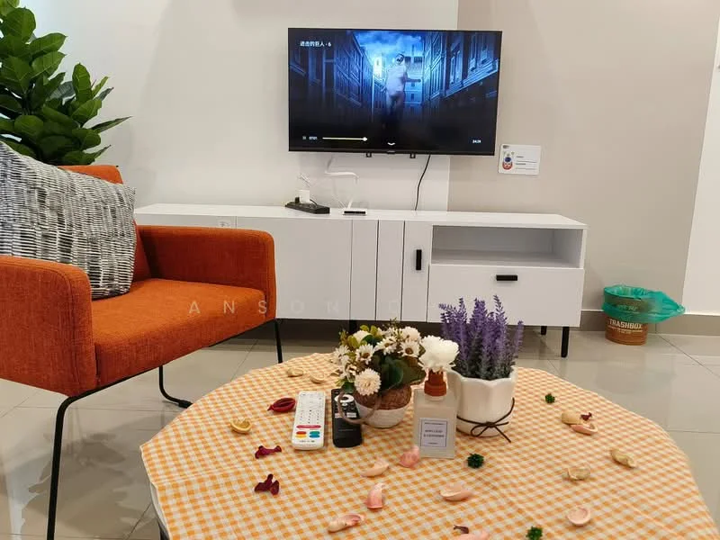 Living features: orange fabric armchair, grey patterned cushion, white TV console, wall-mounted TV, decorative potted plants, coffee table with checkered tablecloth, floral arrangement on table, remote control on table, ceramic vase with lavender, ceramic vase with mixed flowers, tile flooring, neutral wall color, recycling bin in background; style: modern.