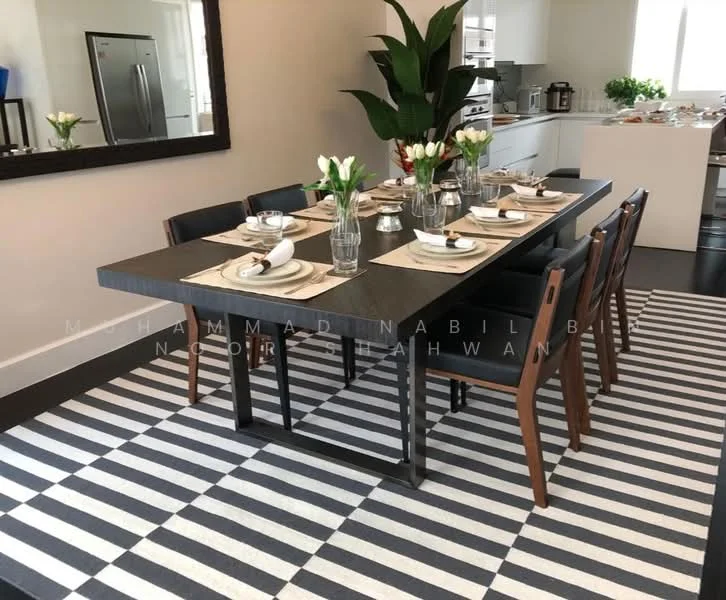 Dining features: 6-seater dining table, black wooden table with metal legs, upholstered dining chairs in brown, white tableware, silver cutlery, glass vases with tulips, striped area rug, wall-mounted mirror, potted plant in corner, light-colored walls, open kitchen in background; style: modern.