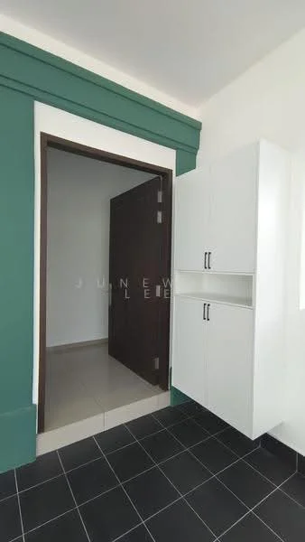 Room features: green accent wall, white cabinetry with two doors, dark wood door, black tile flooring, neutral tile flooring visible through doorway, natural light from doorway; style: modern.