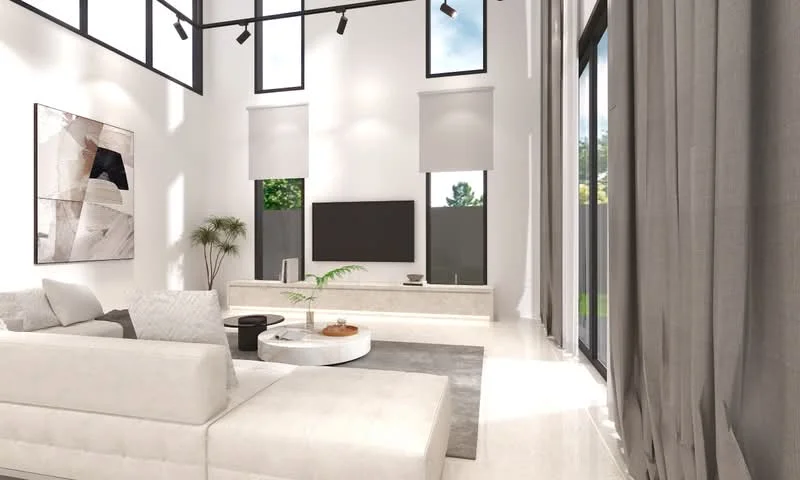 Living features: white painted walls, high ceiling, large floor-to-ceiling windows, grey area rug, light-coloured sectional sofa, round coffee table, wall-mounted TV, decorative plant, recessed lighting, sheer curtains, dark grey throw pillows, light marble flooring; style: modern; view: garden.
