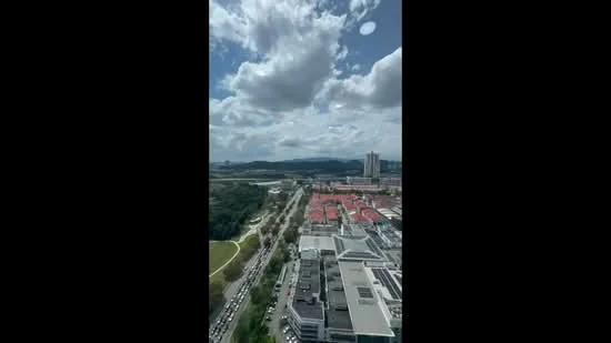 Exterior type: high-rise condominium; features: city skyline view, surrounded by greenery, urban landscape, visible road traffic, nearby residential buildings, cloudy sky; style: modern.