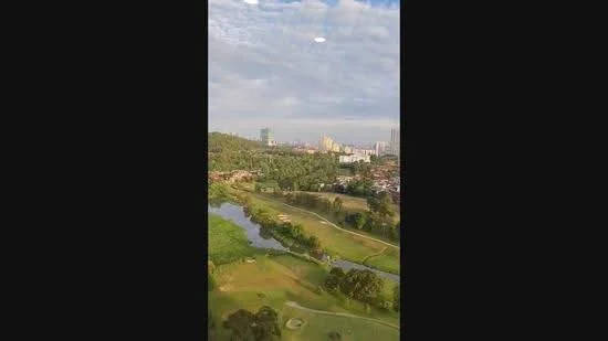 Exterior features: city skyline in background, lush greenery, river view, golf course, hills in distance, cloudy sky.