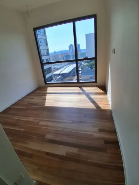 Room features: large window with city view, wooden flooring, white painted walls, natural light, corner room, no visible furniture, minimal decor, neutral color scheme; style: modern; view: city.