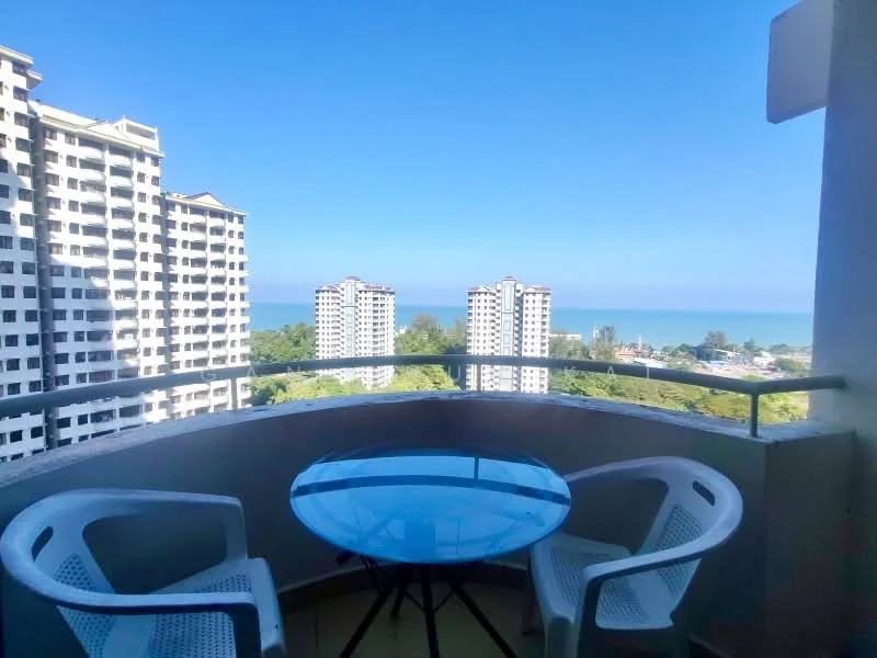 Balcony features: glass table, two white plastic chairs, railing with glass panel, sea view, city view, surrounding greenery; view: sea.