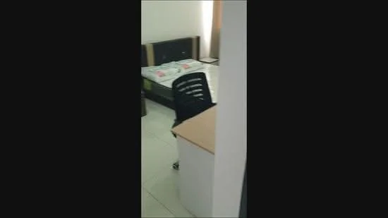 Room features: single bed, black wooden bed frame, white bedding with floral pattern, black plastic chair, white desk, tiled flooring, white walls, curtains, natural light from window.