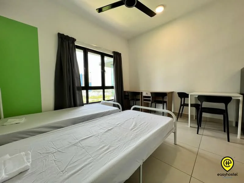 Bedroom features: two single beds with metal frames, white bed linens, green accent wall, white painted walls, floor-to-ceiling windows, black curtains, ceiling fan, light fixture, study desk with two black chairs, tile flooring; style: modern.