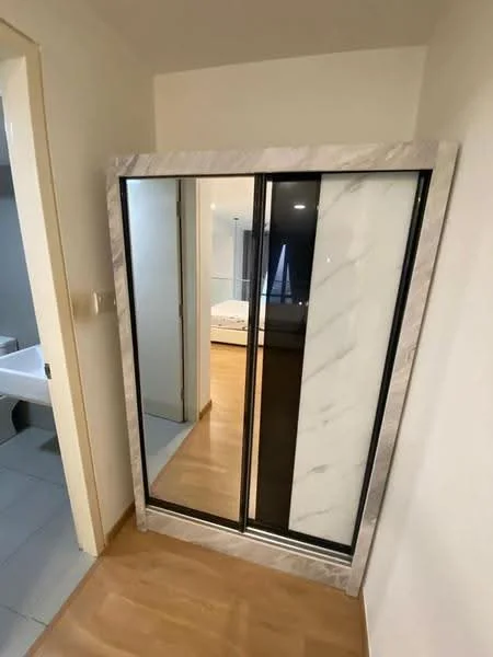 Room features: mirrored sliding wardrobe, marble frame around wardrobe, light wood flooring, neutral painted walls, doorway leading to another room; style: modern.