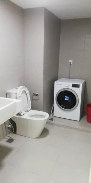 Bathroom features: white wall tiles, grey accent wall, ceramic tile flooring, single-sink vanity with white cabinet, one-piece toilet, front-load washing machine, red plastic bin, wall-mounted electrical outlet; style: modern.