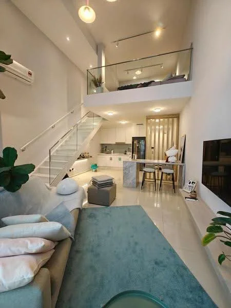 Living features: sofa in light grey fabric, decorative cushions in pastel colors, area rug in light blue, wall-mounted TV, coffee table, floor-to-ceiling windows, 1 wall-mounted split AC, recessed downlights, high ceiling, open-plan layout, glass railing, staircase with white steps, potted plants; style: modern. Kitchen features: white cabinetry, marble countertop, built-in oven, stainless-steel fridge, 4-burner gas hob, sink, open shelving, pendant lighting; style: modern.