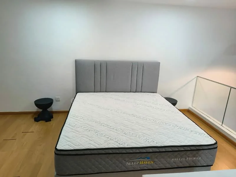 Bedroom features: queen-size bed, upholstered headboard in grey, wooden flooring, two black bedside tables, white walls, minimalist decor; style: modern.