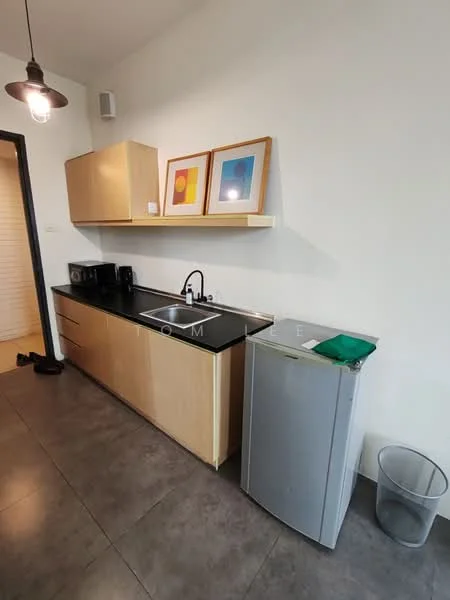 Kitchen features: black countertop, single-bowl stainless-steel sink, chrome pull-down faucet, wood cabinetry, microwave, black coffee machine, small fridge, grey waste bin, framed artwork on wall, pendant light fixture, grey tile flooring, white painted walls; style: modern.
