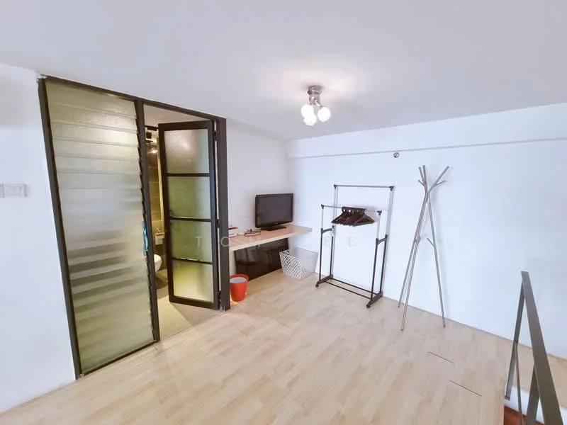 Room features: light wood flooring, white painted walls, glass sliding door, ceiling light fixture with three bulbs, wall-mounted TV, small desk, clothes rack, laundry basket, decorative coat rack; style: modern.